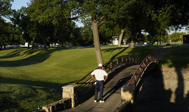  Harold Varner III examines his ball that landed on a bridge after his tee shot on the 10th hole during the second round of the Charles Schwab Challenge on Friday. Varner shot a 66 to take a one-shot lead. David J. Phillip | AP photo 