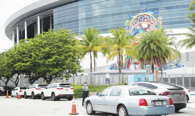  Vehicles pass by the home run sculpture as they wait in line on Monday outside of Marlins Park at a COVID-19 testing site in Miami. The long line of cars each morning as players arrive at work provides a reminder of the risks when they leave. Lynne Sladky | AP photo 