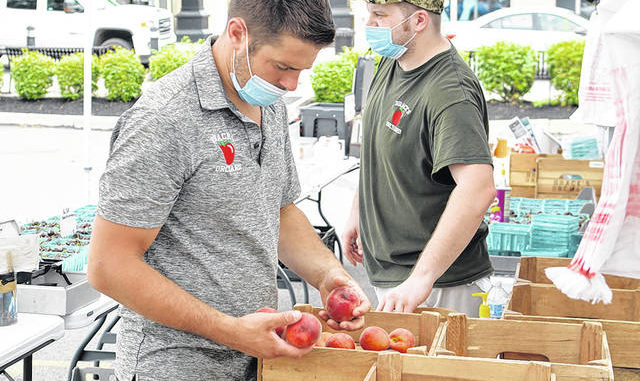  Logan Brace, left, and Joe Erzar, from Braces Orchard replenish produce at the annual Farmers Market in downtown Pittston on Tuesday. Tony Callaio | For Sunday Dispatch 