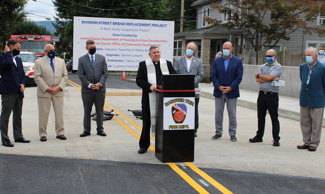  The Rev. Richard Cirba of Exaltation of the Holy Cross Church in Hanover Township blesses the new Division Street bridge with prayer and holy water at a ribbon-cutting ceremony on Thursday. Jerry Lynott | Times Leader 