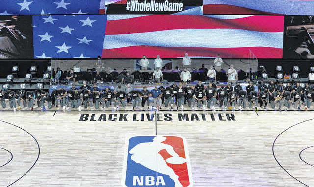  Members of the New Orleans Pelicans and Utah Jazz kneel together around the Black Lives Matter logo on the court during the national anthem before the start of an NBA game Thursday in Lake Buena Vista, Fla. AP photo 