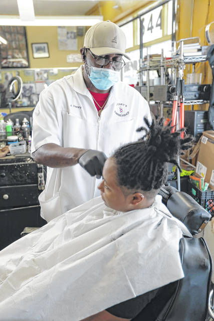 <p>J Henry, owner of J Henry’s barber shop, cuts Deanna Washington’s hair.</p> <p>AP photo</p>