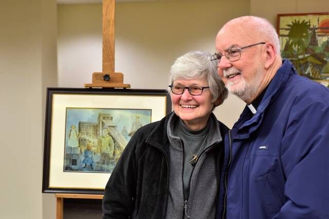 Local artist Sue Hand joins former Kings College President The Rev. Thomas OHara near her painting of the Dorrance breaker Thursday night. The painting was purchased and donated to Kings and unveiled Thursday during an Anthracite Heritage Month event.
                                 Mark Guydish | Times Leader