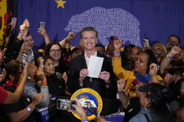 
			
				                                California Gov. Gavin Newsom signs the fast food bill surrounded by fast food workers at the SEIU Local 721 in Los Angeles, on Thursday, Sept. 28, 2023. Anneisha Williams, right, who works at a Jack in the Box restaurant in Southern California celebrates as she holds up the bill.
                                 Damian Dovarganes | AP photo

			
		