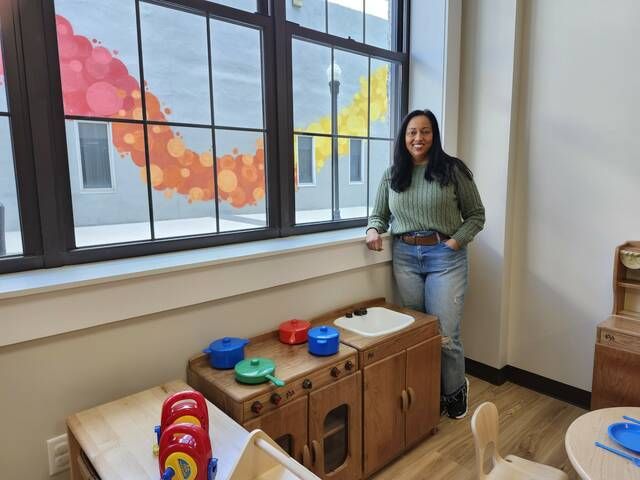 Zubeen Saeed, president and CEO of Building Blocks Leanring Centers, stands next to child-sized furniture in his newest center, located in the second block of South Main Street in downtown Wilkes-Barre.  Through the windows you can see a colorful mural she painted on the wall opposite.